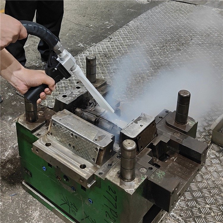 Industrial dry ice cleaning machine blasting pellets onto a metal surface, removing grease without chemicals
